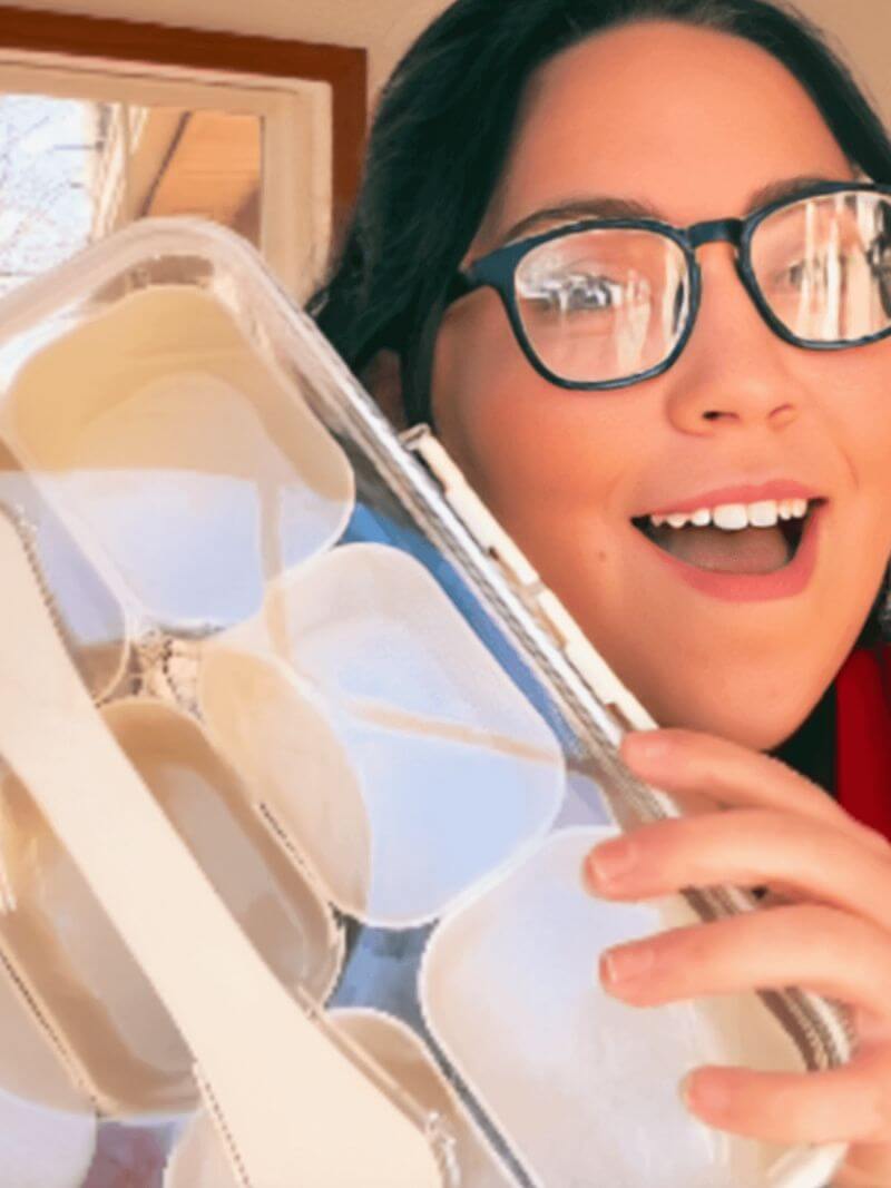 Person holding a snack container with round handle, smiling