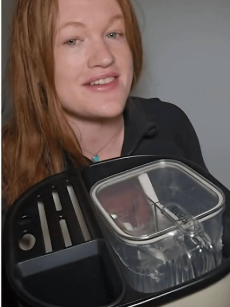Person holding a spice organizer with a clear lid, possibly a kitchen item.