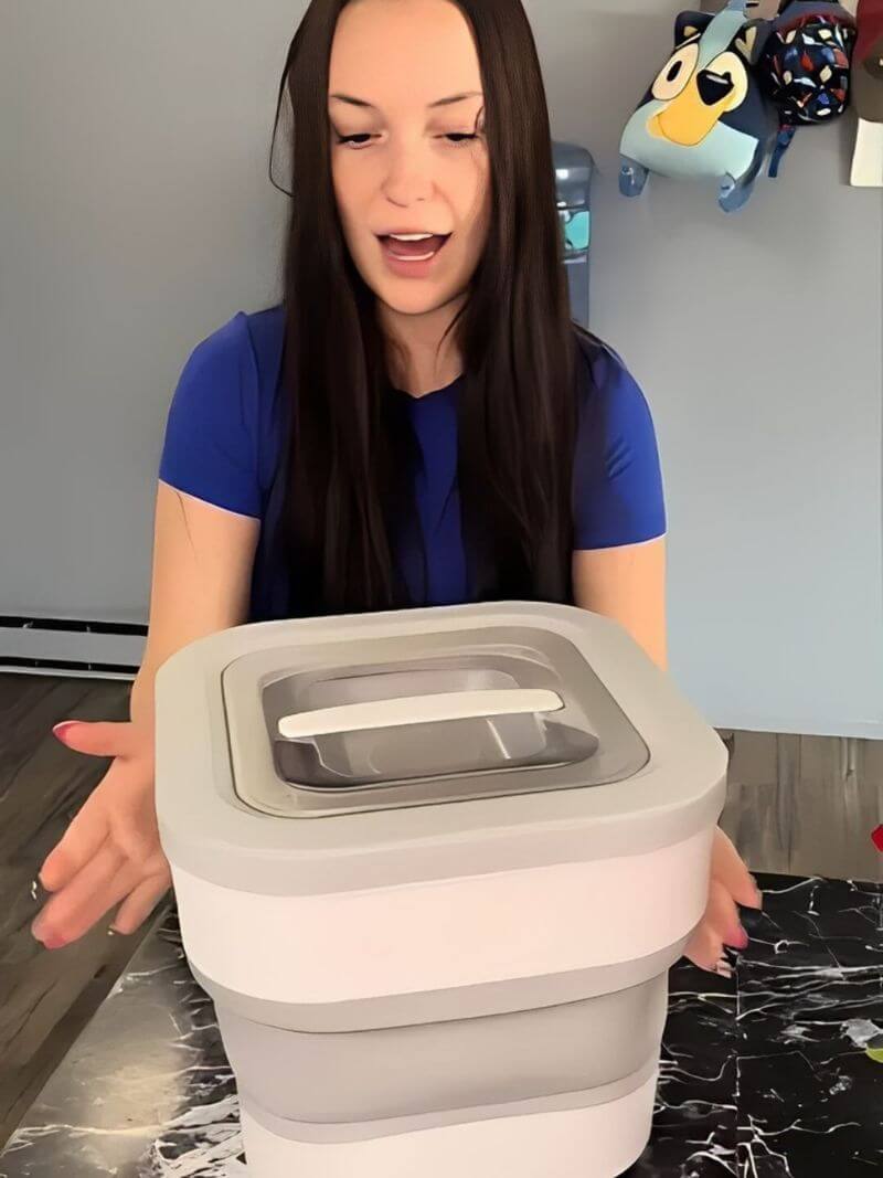 Woman holding a gray and white collapsible container on a marble surface.