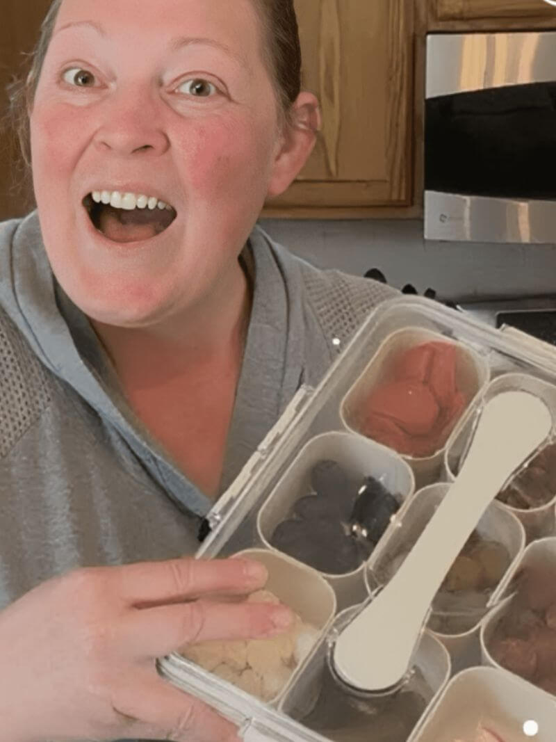 Person holding a set of snackle box with food items in a kitchen setting.