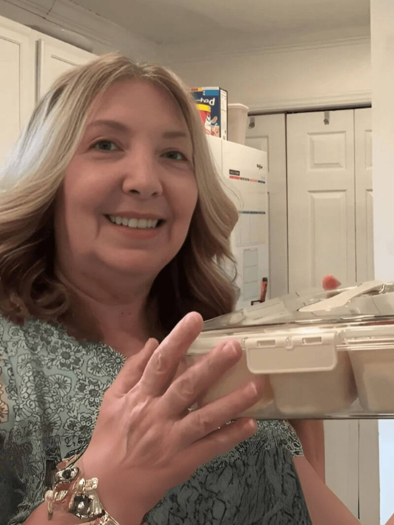Woman holding a plastic container in a kitchen setting