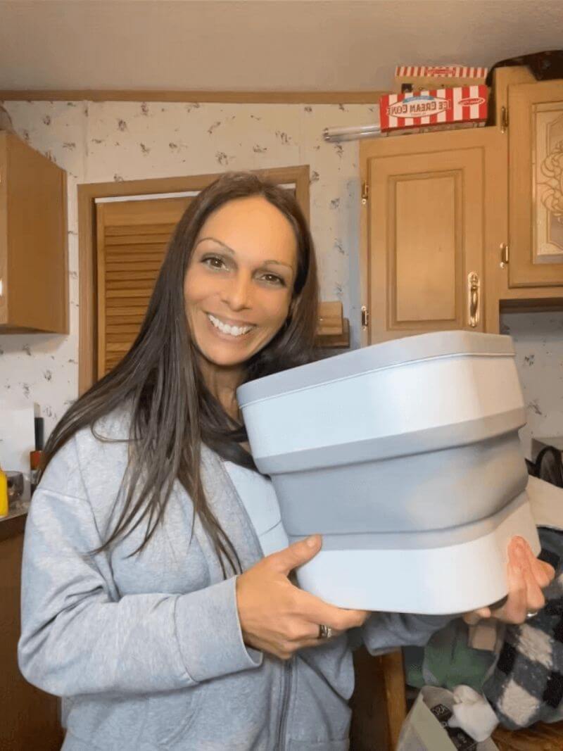 Woman holding a large collapsible container in a kitchen