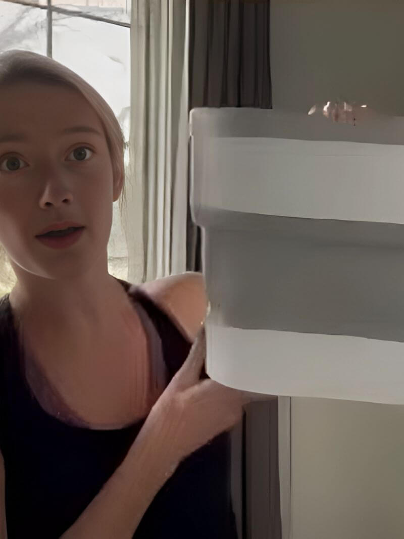 Person holding a collapsible container near a window